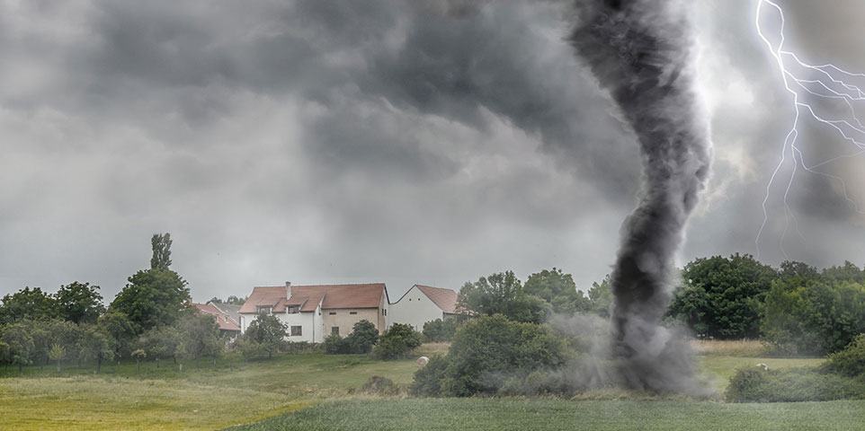 A tornado moving across open farmland with lightning behind it